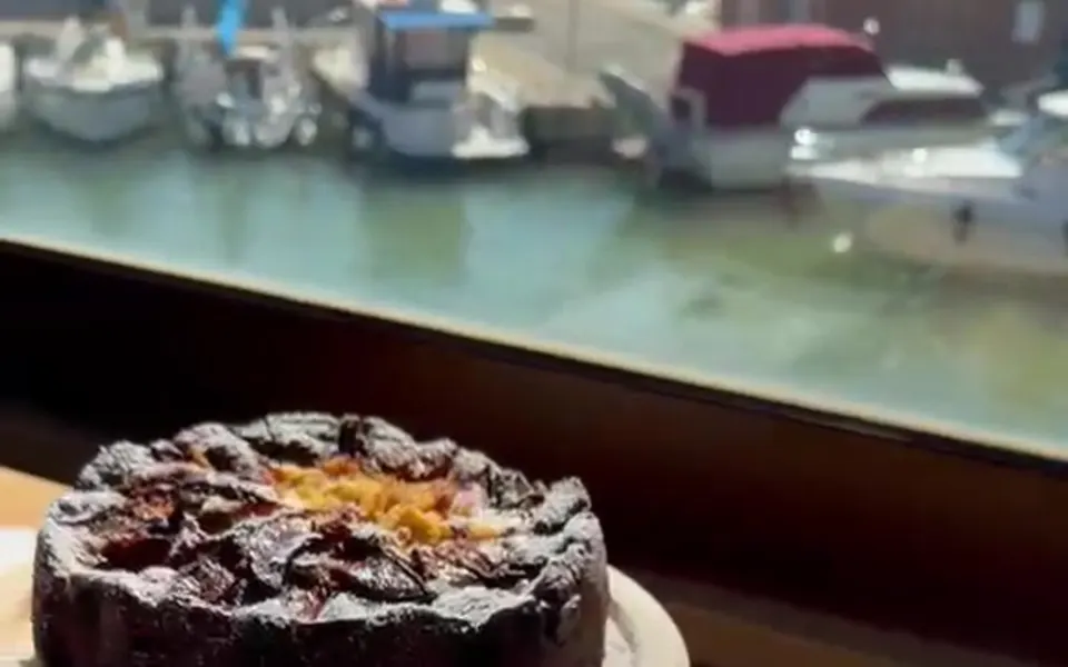 La vetrata di Brasa sul porto, con le barche ormeggiate e due dolci in primo piano